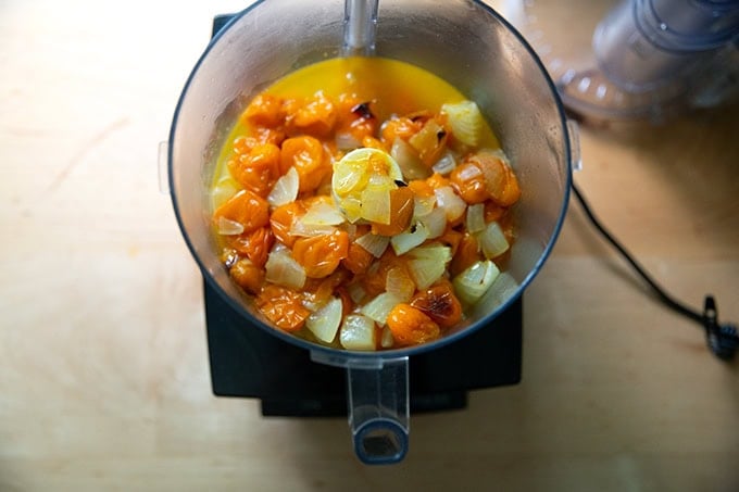 A food processor filled with roasted yellow tomatoes and onions.
