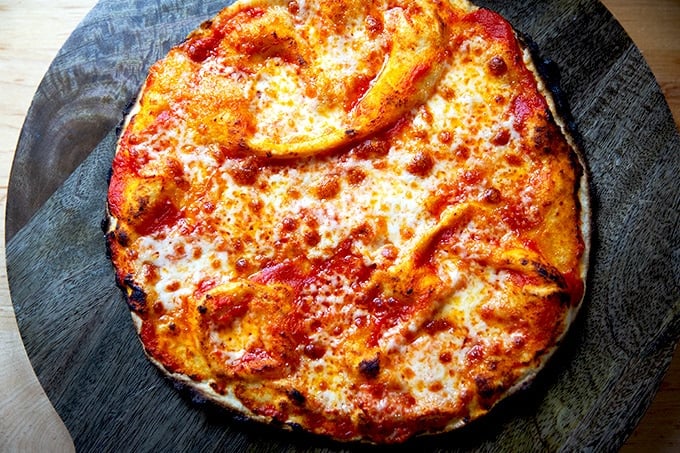 Just-baked gluten-free Margherita pizza on a cutting board.