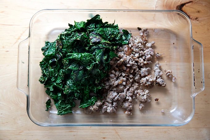 A 9x13-inch pan filled with sautéed kale and browned sausage.