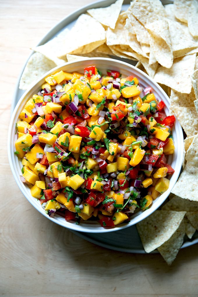 A bowl of mango salsa aside chips.