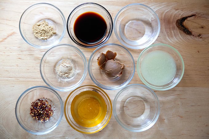 Ingredients to make miso lime sauce all measured out in small glass bowls.