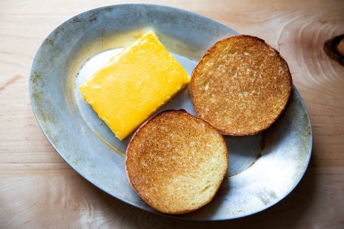 Toasted brioche aside melted cheese-topped egg slice.