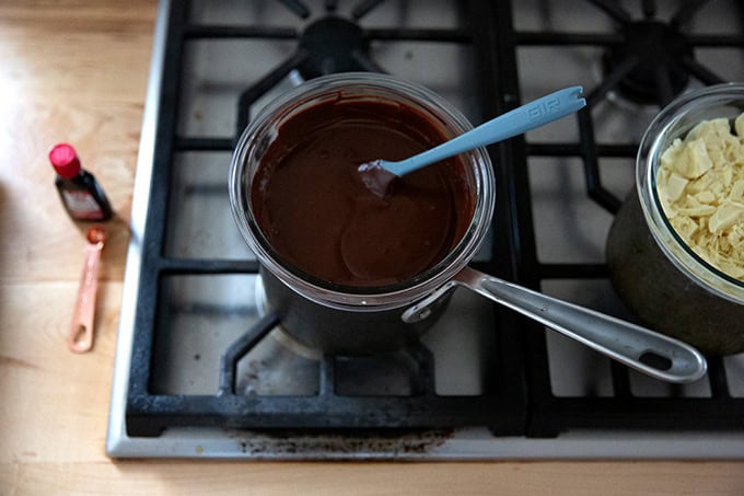 A bowl of melted dark chocolate set over a pot of boiling water on the stovetop.