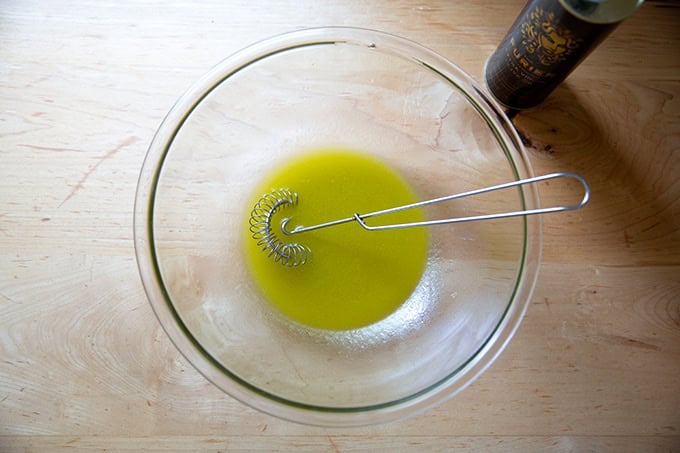 A large bowl filled with honey, white balsamic vinegar, fresh lemon juice, salt, and extra-virgin olive oil all whisked together.