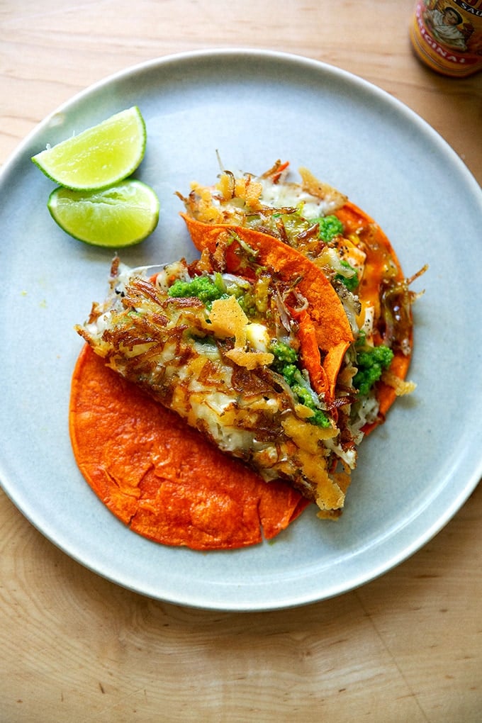 A plate of crispy potatoes, egg, and cheese on tortillas.