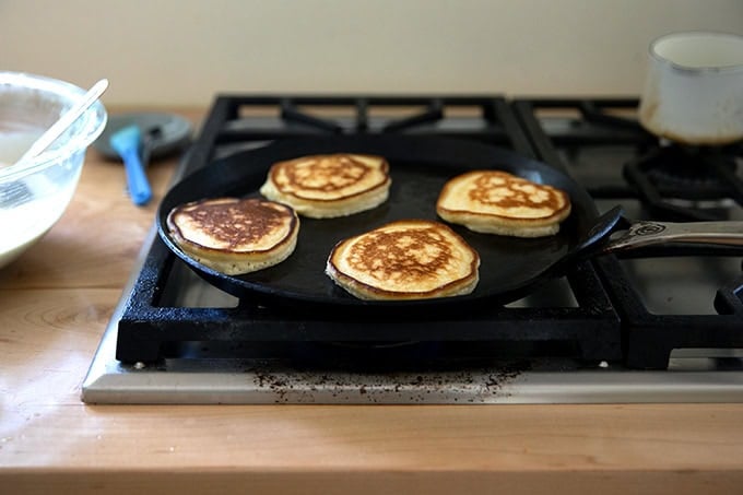 Sourdough discard pancakes cooking in a skillet.