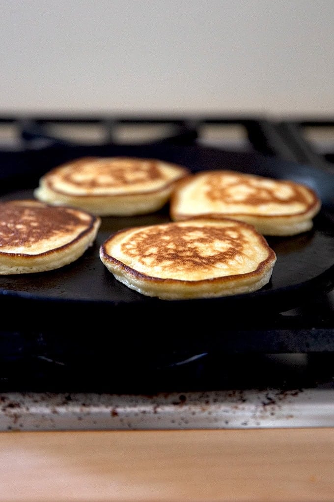 Sourdough discard pancakes cooking in a skillet.