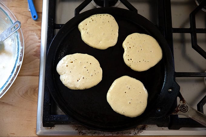 Sourdough discard pancakes cooking in a skillet.
