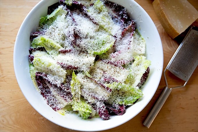 A bowl of Caesar salad covered with finely grated parmesan.