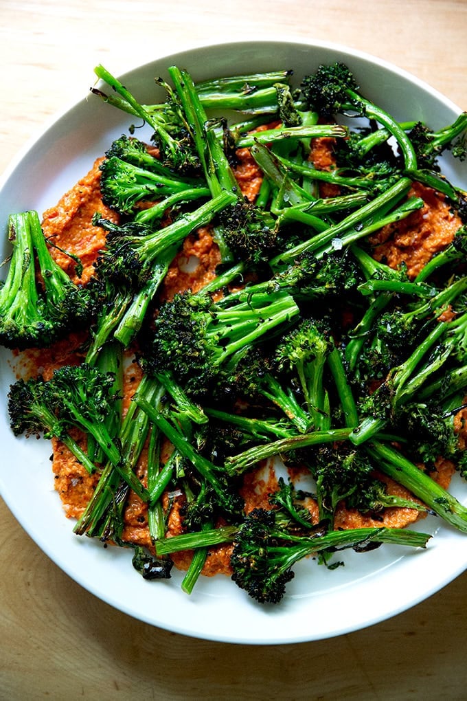 A platter spread with romesco and topped with charred broccolini.