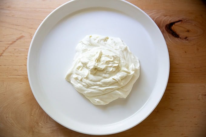 A platter with a heap of whipped ricotta in the center, not yet spread to the edges.