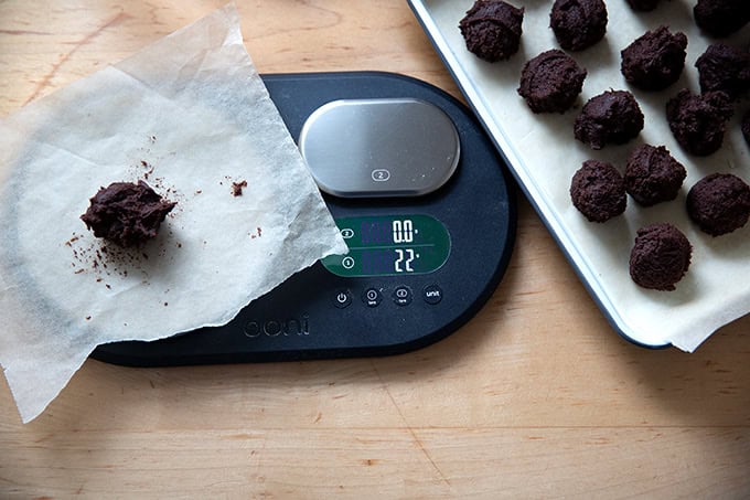 Portioned chocolate crinkle cookie dough balls on a scale.