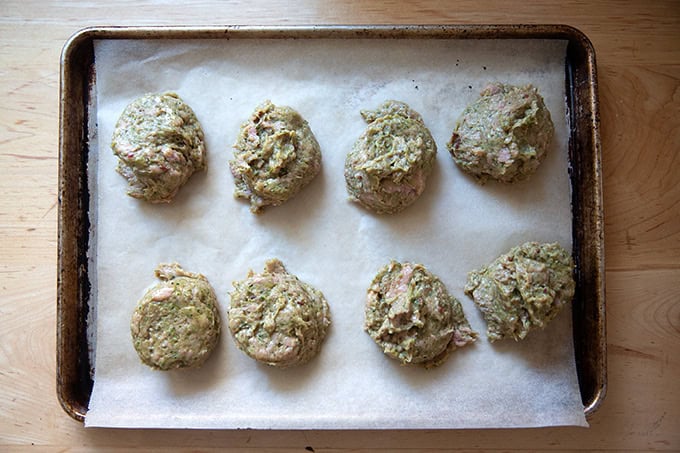 Portioned turkey burger mixture on a parchment-lined sheet pan.