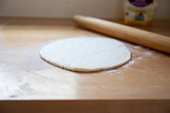 A rolled out gluten-free pizza crust on a countertop.