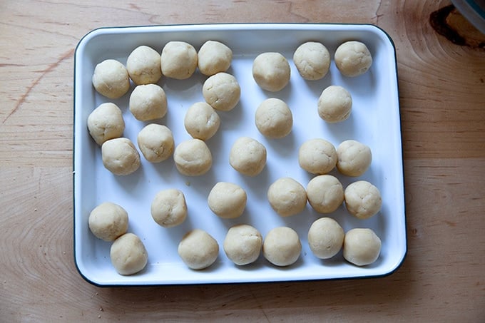 A tray of rolled lemon-almond snowball cookie dough balls.