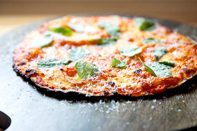 Side view of a just-baked, gluten-free Margherita pizza on a cutting board.