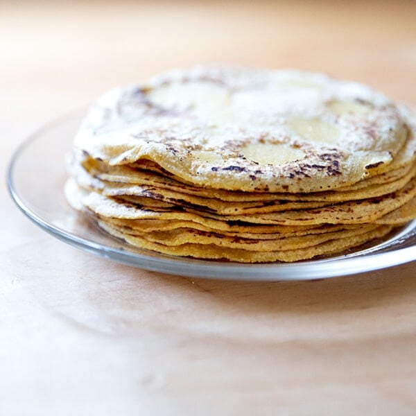 A stack of homemade corn tortillas on a plate.