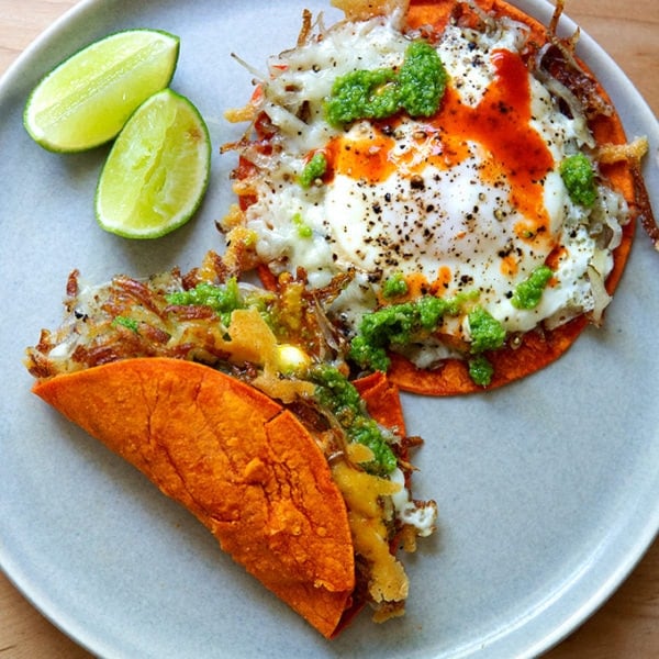 A plate of crispy potatoes, egg, and cheese on tortillas.