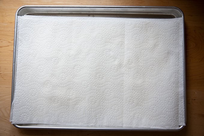 Ricotta draining on a paper-towel-lined sheet pan.