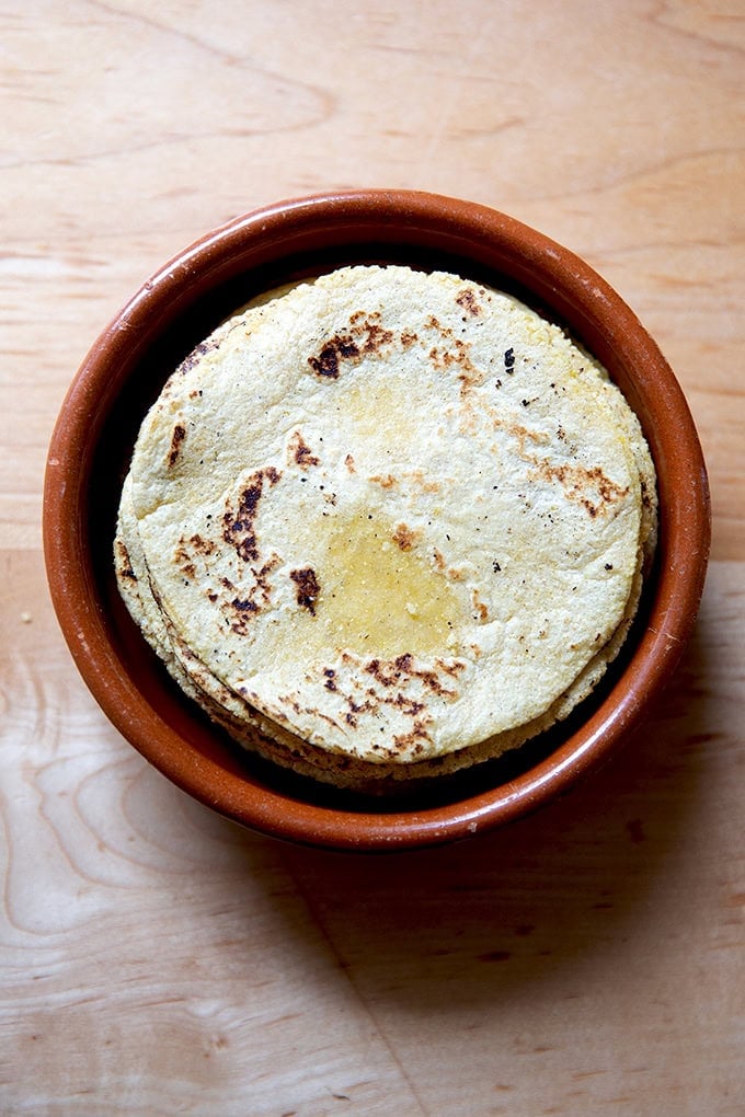 A small ceramic dish filled with a stack of homemade corn tortillas.