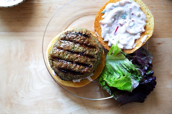 A plated turkey burger aside some lettuce, bun spread with raita.