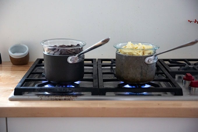 Two pots holding two bowls of chocolate set over boiling water.