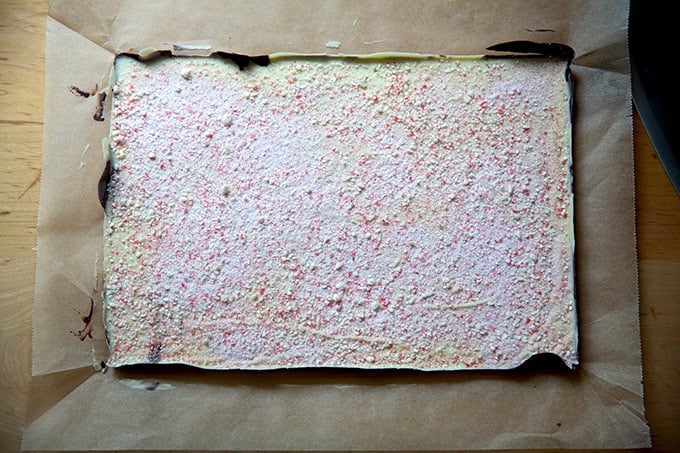 A full sheet of uncut peppermint bark on a sheet of parchment paper.