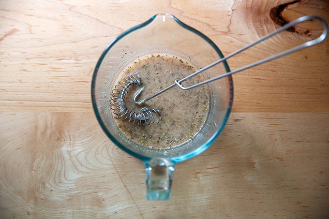 A liquid measure filled with red wine vinegar, lemon juice, salt, sugar, mustard, garlic, and oregano all whisked together.