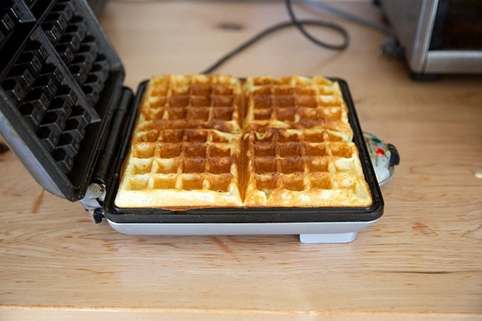 A waffle iron open and filled with just-cooked sourdough discard waffles.
