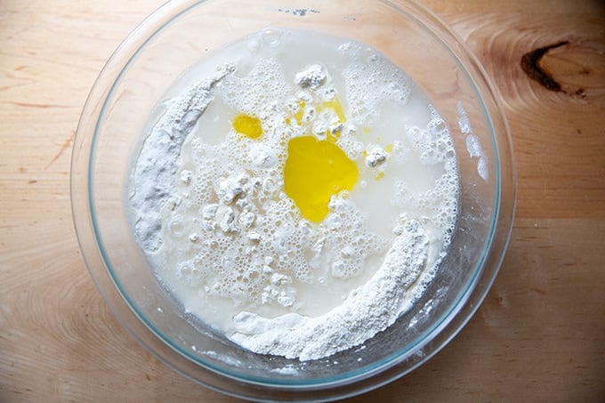 Water and olive oil added to the bowl of ingredients for pretzel roll dough.