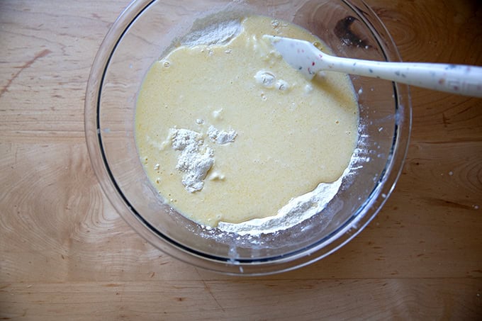 The wet ingredients added to the dry ingredients to make sourdough discard waffles in a large bowl.