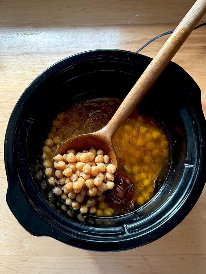 A pot of chickpeas with a bean spoon inside.