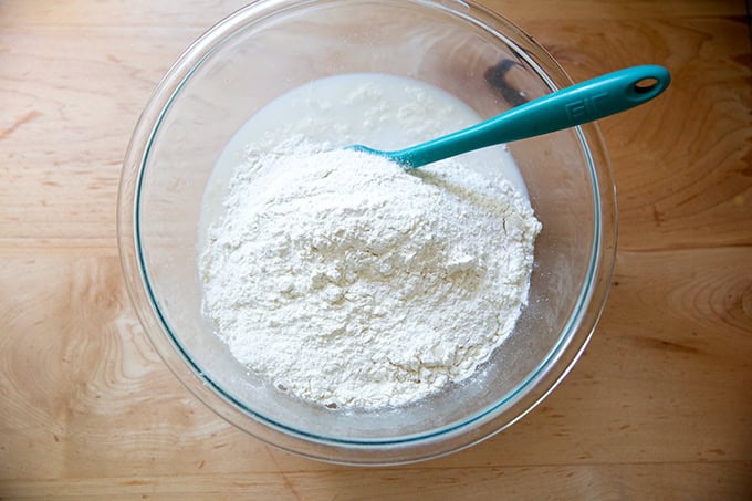 A large bowl holding water, yeast, salt, honey, sourdough discard and flour, not yet stirred together.