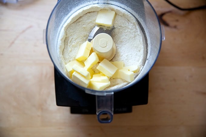 A food processor filled with the dry ingredients for a crisp topping, blended together, with the butter just added.