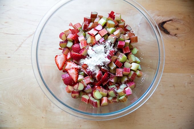 A large bowl filled with strawberries and rhubarb, sugar, lemon zest, and cornstarch.