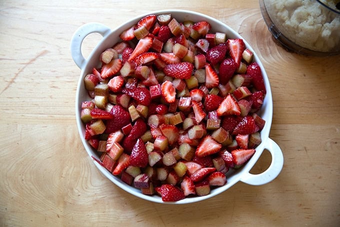 A baking dish filled with strawberries and rhubarb tossed with sugar, lemon zest, and cornstarch.