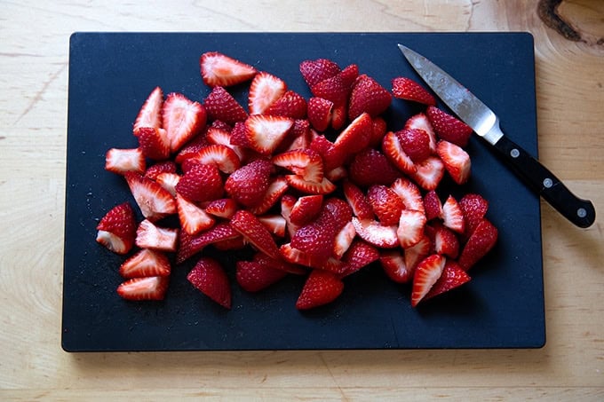 A cutting board topped with sliced strawberries.