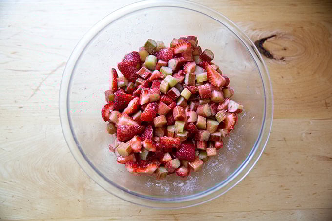 A bowl of cut strawberries and rhubarb tossed with sugar, cornstarch, and lemon zest.