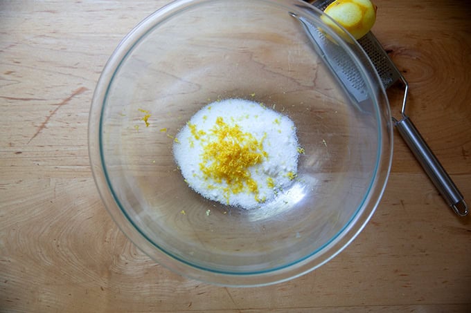 A large bowl filled with 1/2 cup of sugar and the zest of 1 lemon.