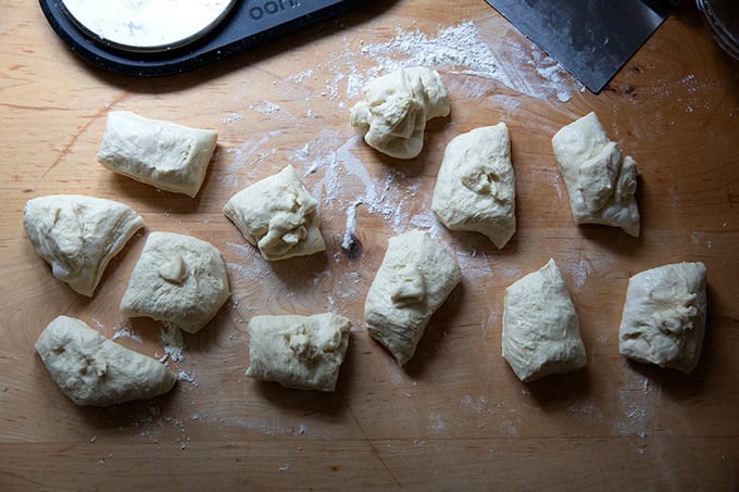 Twelve portioned pieces of brioche dough on a countertop.