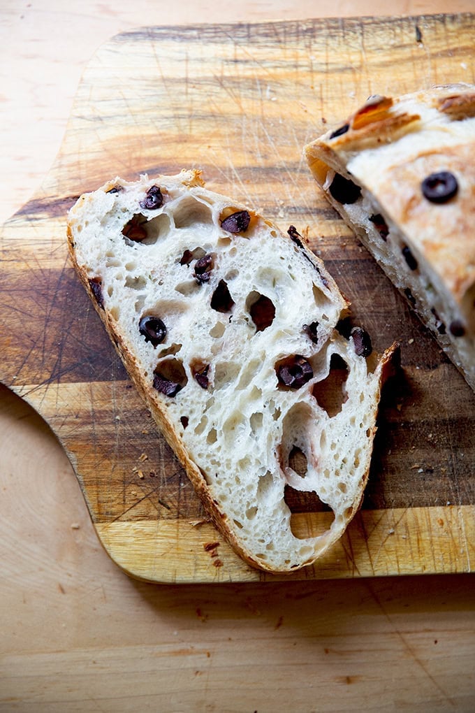 A slice of rosemary-olive sourdough on a cutting board.