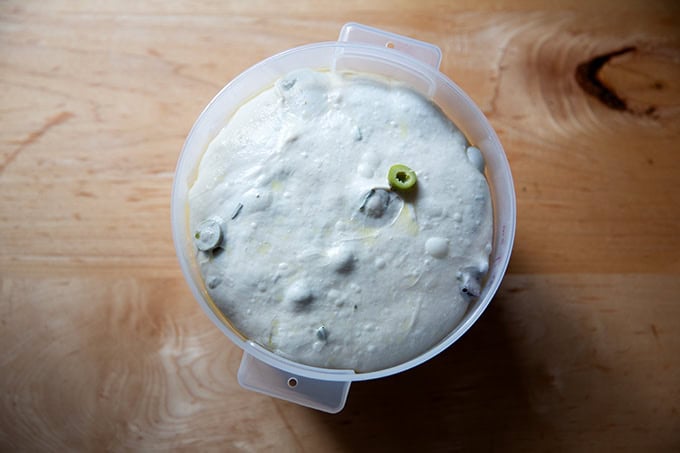 A 2-quart dough storage container filled with rosemary-olive sourdough dough risen nearly to the top.