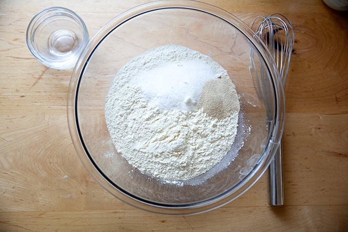 The dry ingredients to make brioche hot dog buns in a large glass bowl.
