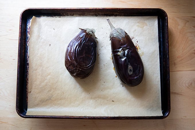 Two roasted eggplants on a sheet pan.