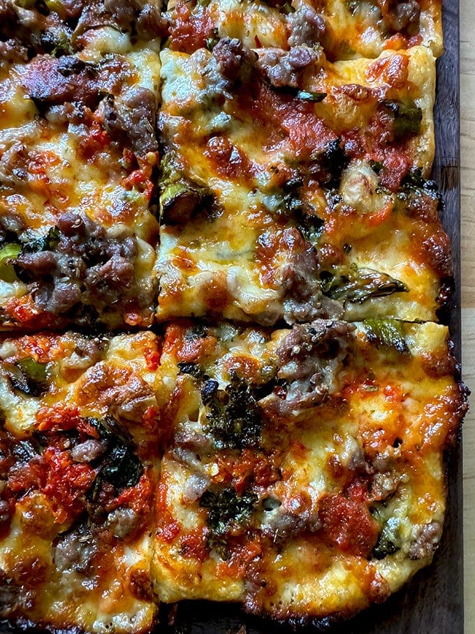 Grandma-style pizza on a cutting board cut into square slices.