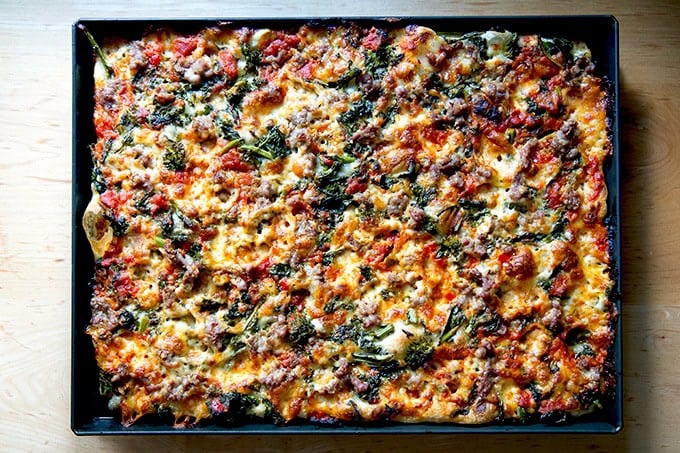 Just-baked grandma-style pizza topped with sausage, broccoli rabe, mozzarella and calabrian chile-spiked tomato sauce still in its pan.