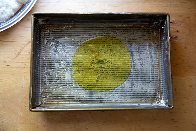 A buttered 9x13-inch pan with 2 tablespoons of olive oil in the center.