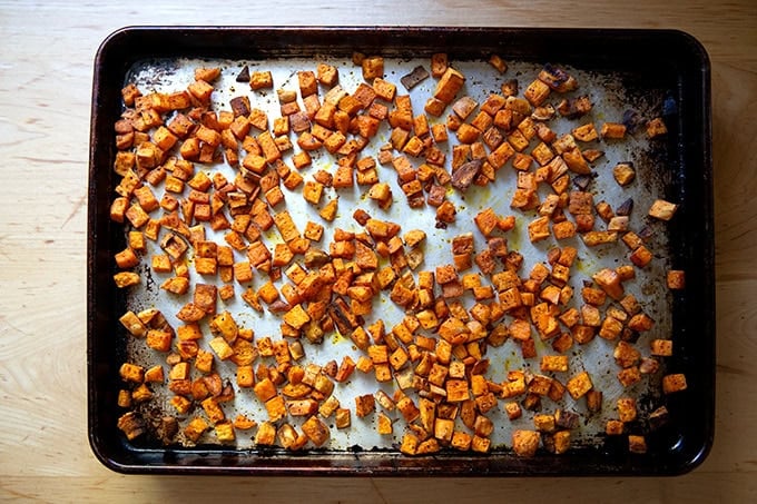 Roasted sweet potato cubes on a sheet pan, rested for a few minutes then tossed with a spatula.