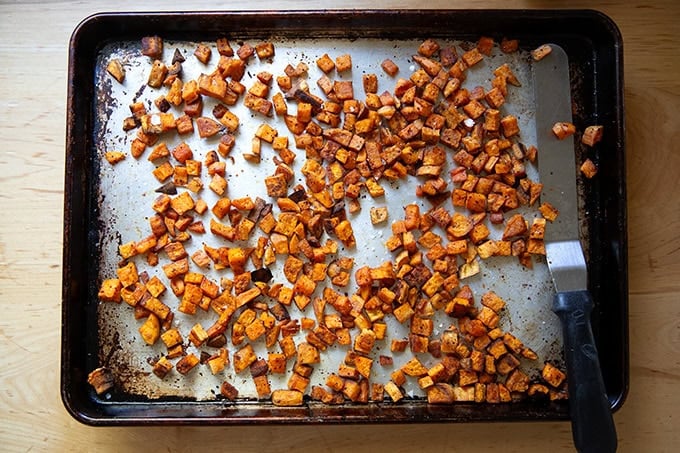 Roasted sweet potato cubes on a sheet pan.