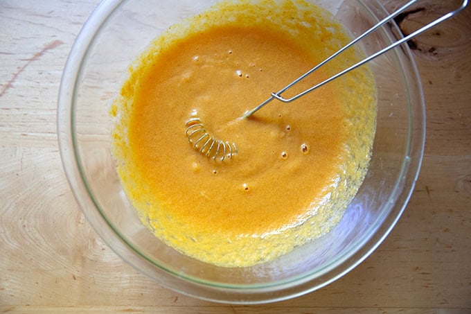The wet ingredients to make pumpkin muffins in a large bowl all whisked together.